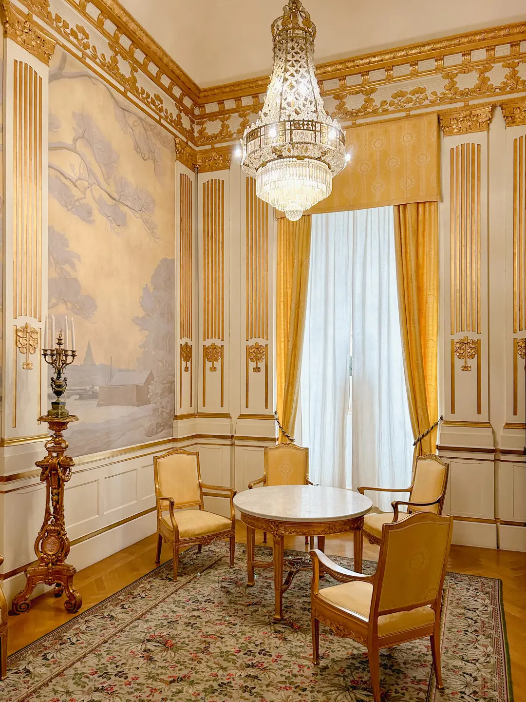 Rum med förgyllda detaljer och en väggmålning föreställande ett vinterlandskap.