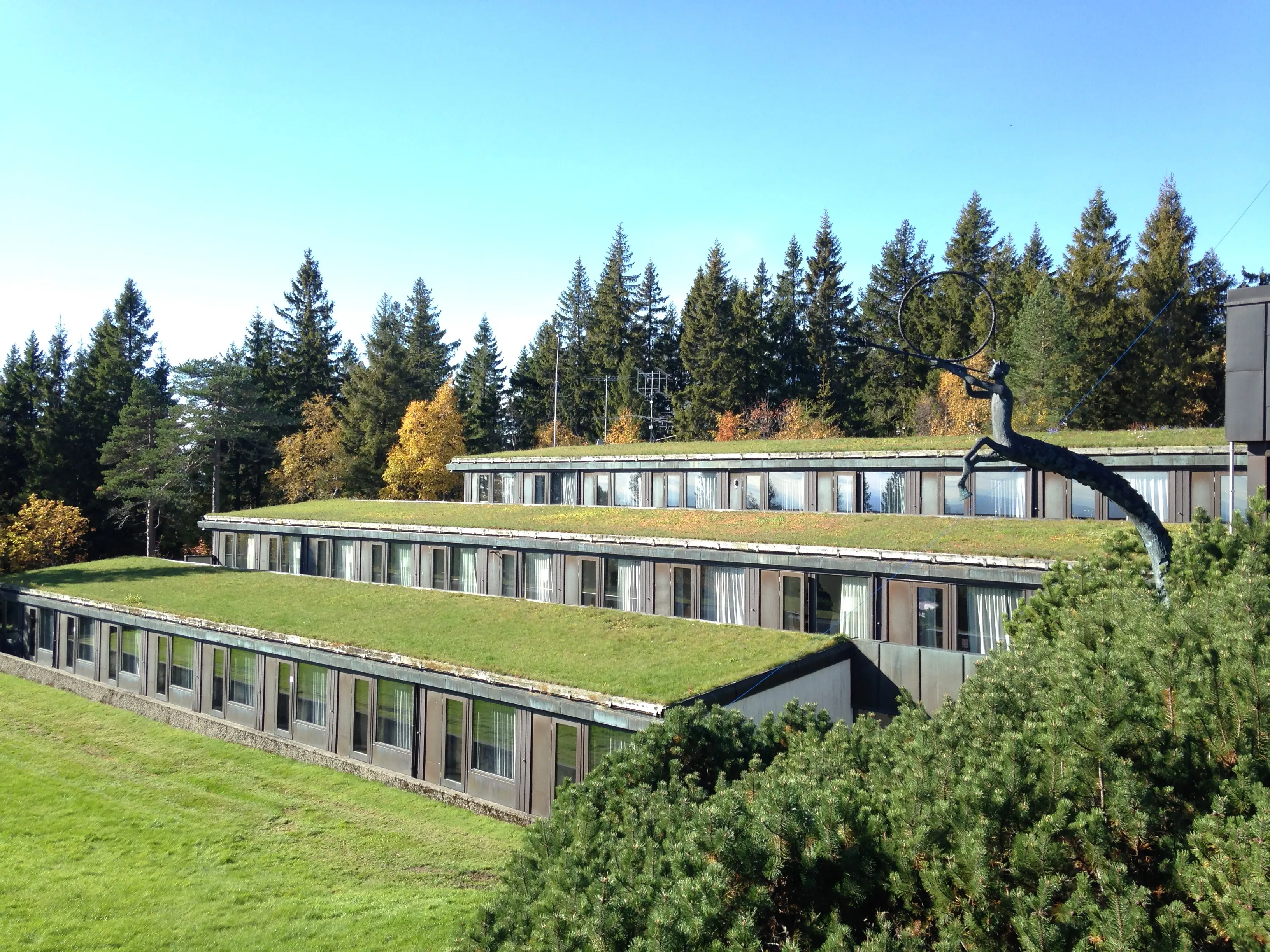 Voksenåsen. Terrasserad byggnad med hotellrum. Taken är gräsbevuxna. Tidig höst.