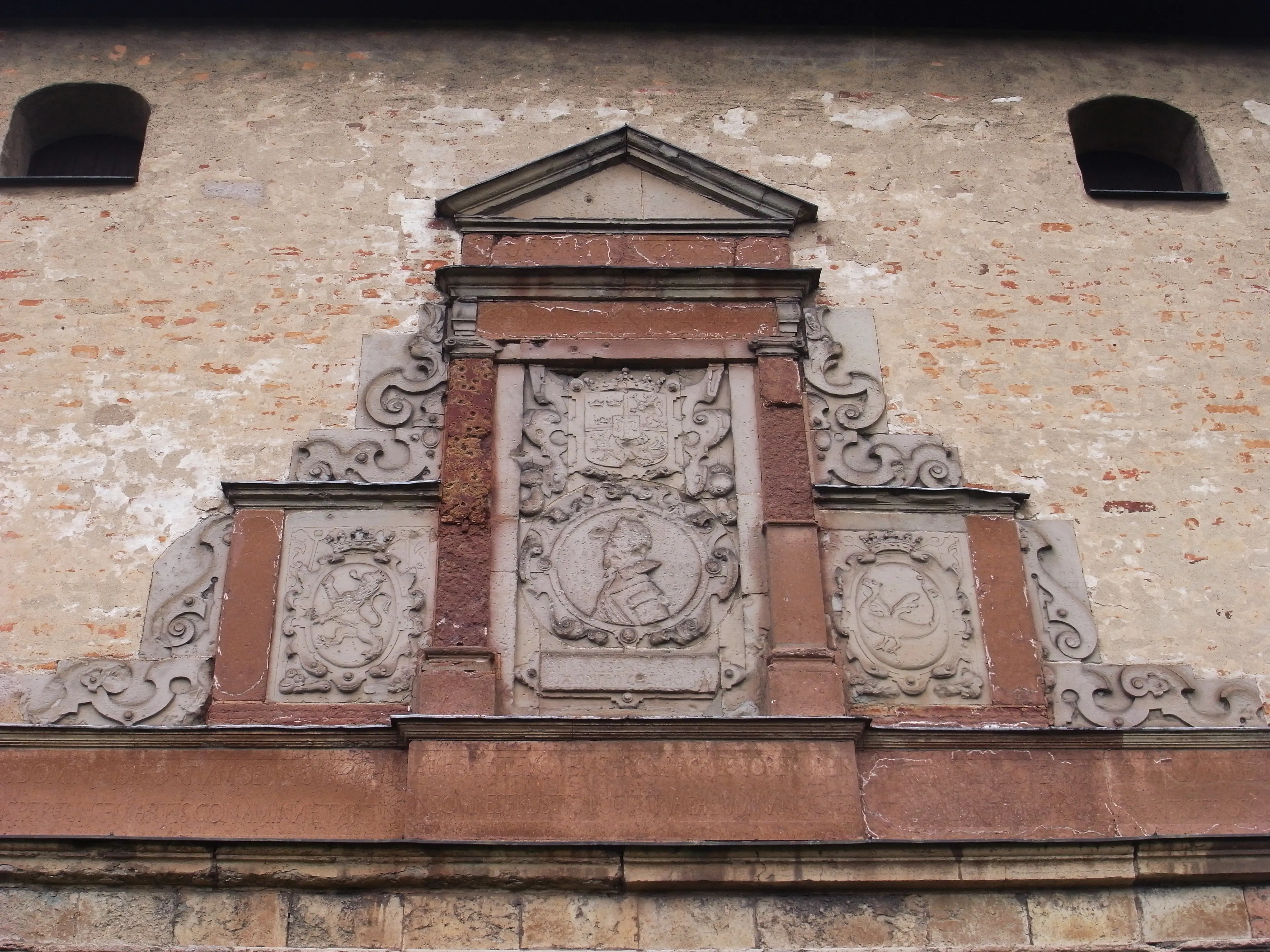 Detalj av fasaden på porttornet vid Johannisborgs slottsruin. Stenreliefer med vapensköldar och ett porträtt.