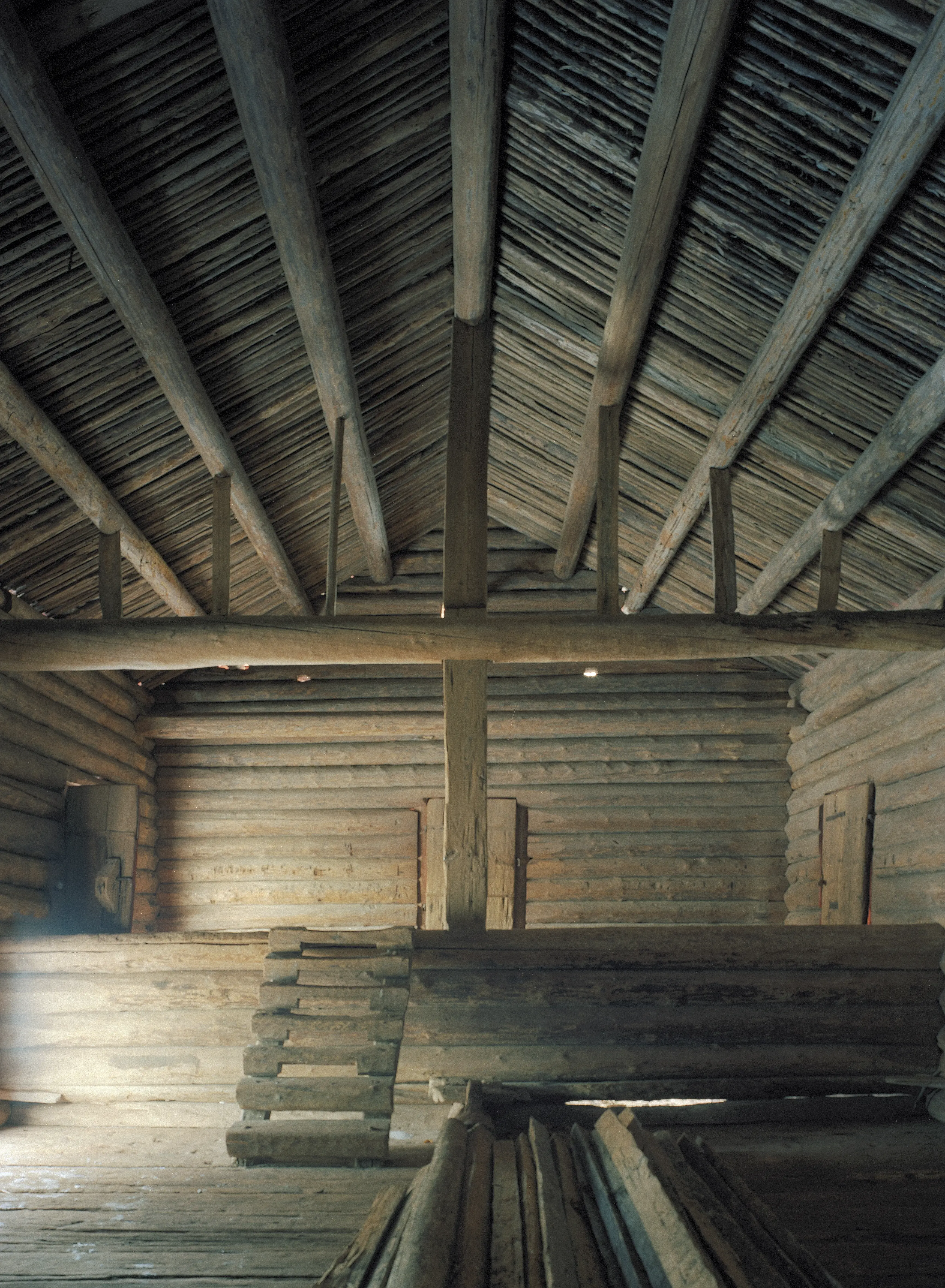 Rankhyttan, interiör. Enkel timmerlada med öppet upp till nock. En del av golvet är upphöjd och dit leder en liten trappa.
