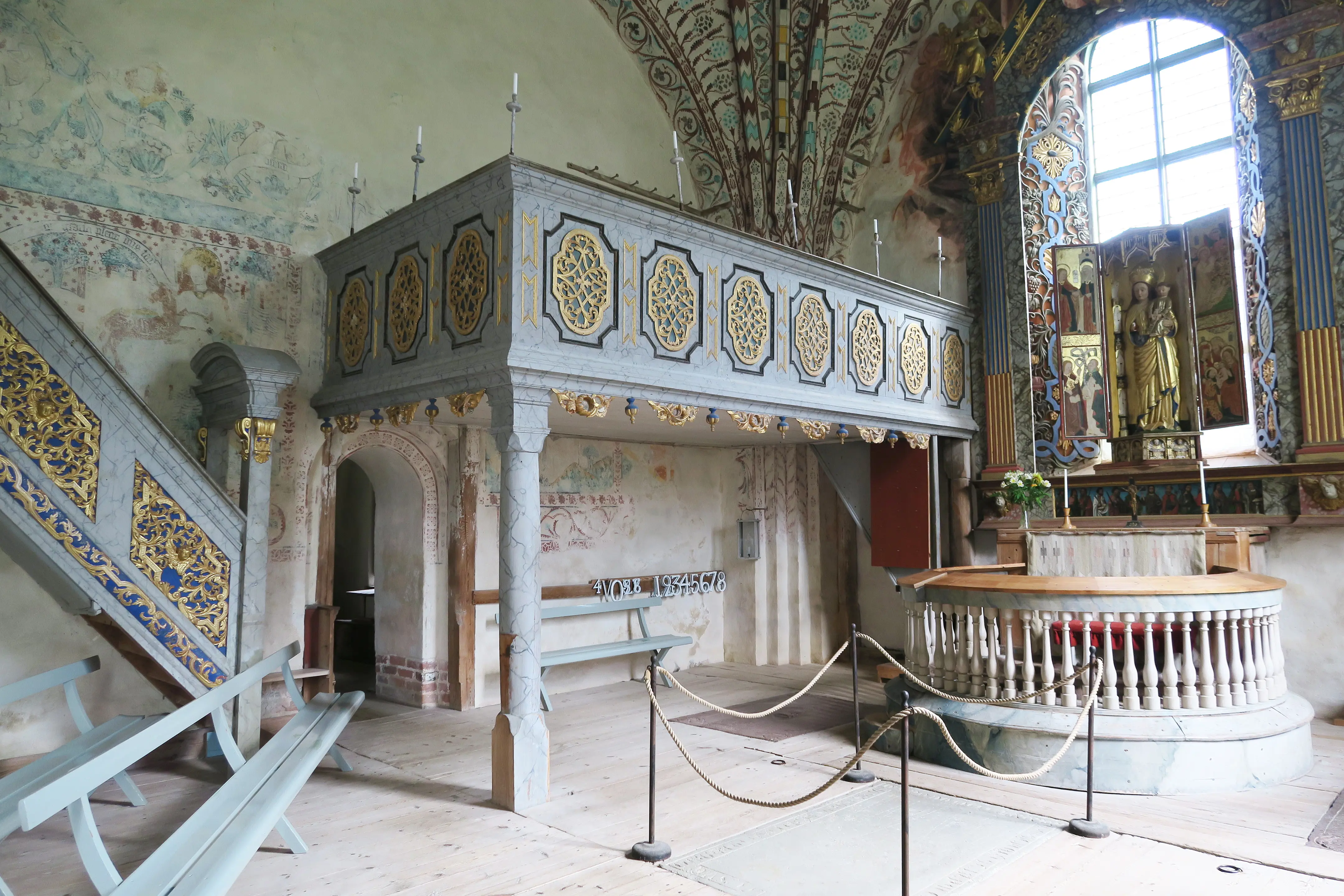 Enångers gamla kyrka. Koret med förgyllt altarskåp och träinredning med förgyllda detaljer. Tak och väggar har målningar.