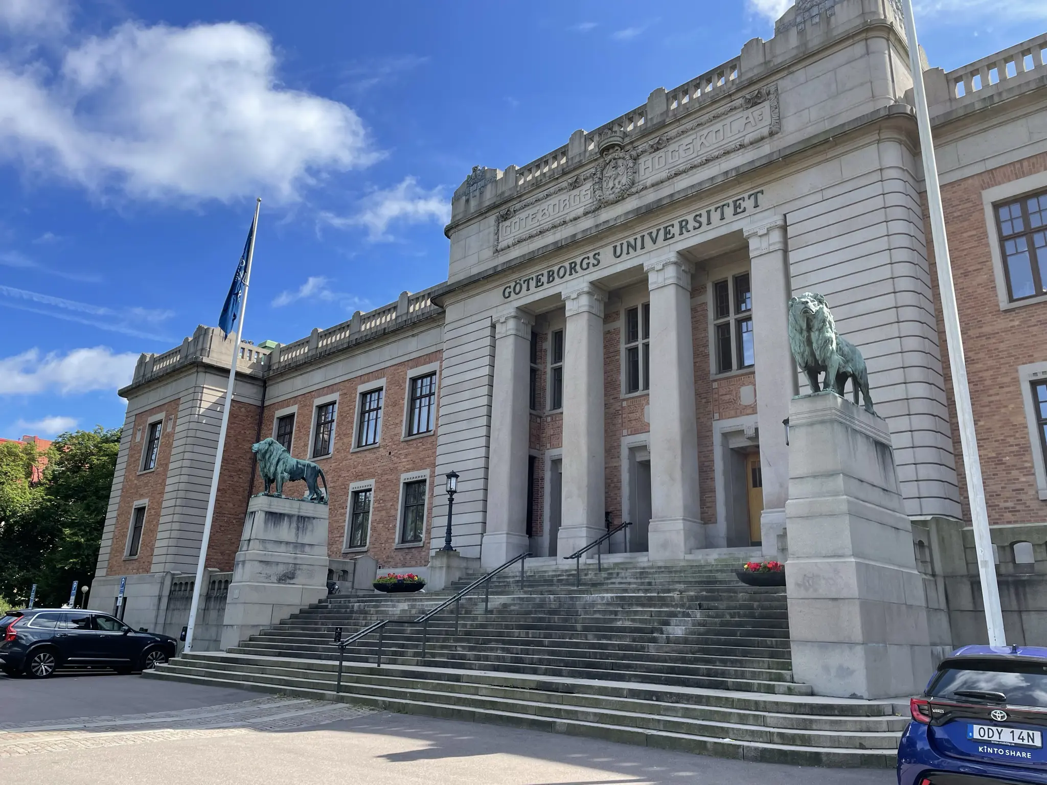 Göteborgs universitet, entréfasaden. En bred stentrappa leder upp till den enorma stenportalen. Två höga stensocklar med bronslejon ramar in trappan.