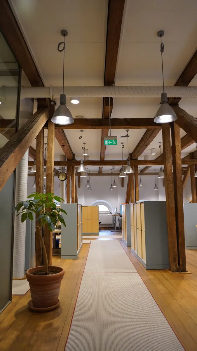 Modern kontorsmiljö med en bevarad bjälkkonstruktion av trä.