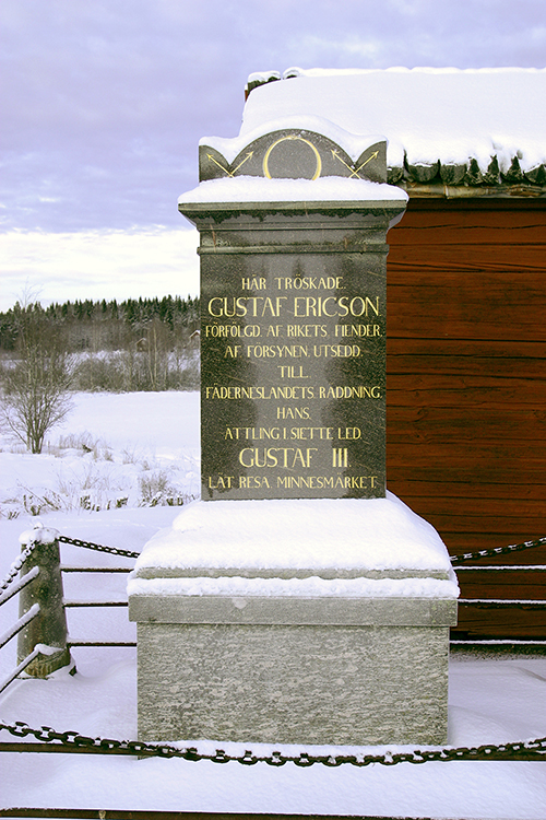 Minnessten med texten: HÄR TRÖSKADE. GUSTAF ERICSON. FÖRFÖLGD AF RIKETS FIENDER. AF FÖRSYNEN UTSEDD. TILL. FÄDERNESLANDETS RÄDDNING. HANS ÄTTLING 1.SIETTE LED GUSTAF III. LÄT RESA MINNESMÄRKET.