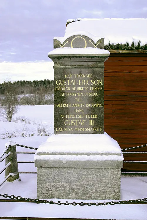 Minnessten med texten: HÄR TRÖSKADE. GUSTAF ERICSON. FÖRFÖLGD AF RIKETS FIENDER. AF FÖRSYNEN UTSEDD. TILL. FÄDERNESLANDETS RÄDDNING. HANS ÄTTLING 1.SIETTE LED GUSTAF III. LÄT RESA MINNESMÄRKET.