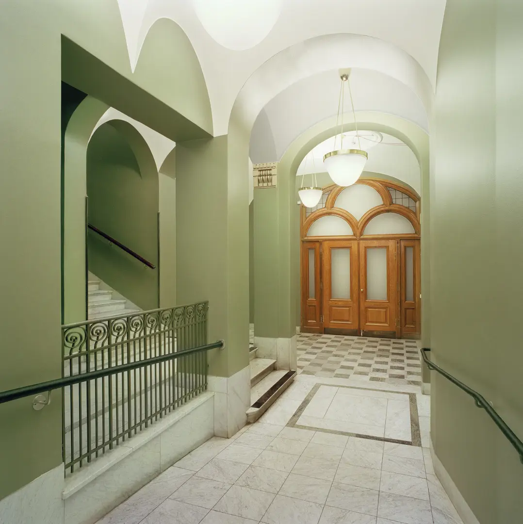 Trapphus målat i en grön nyans med trädörrar med frostat glas.