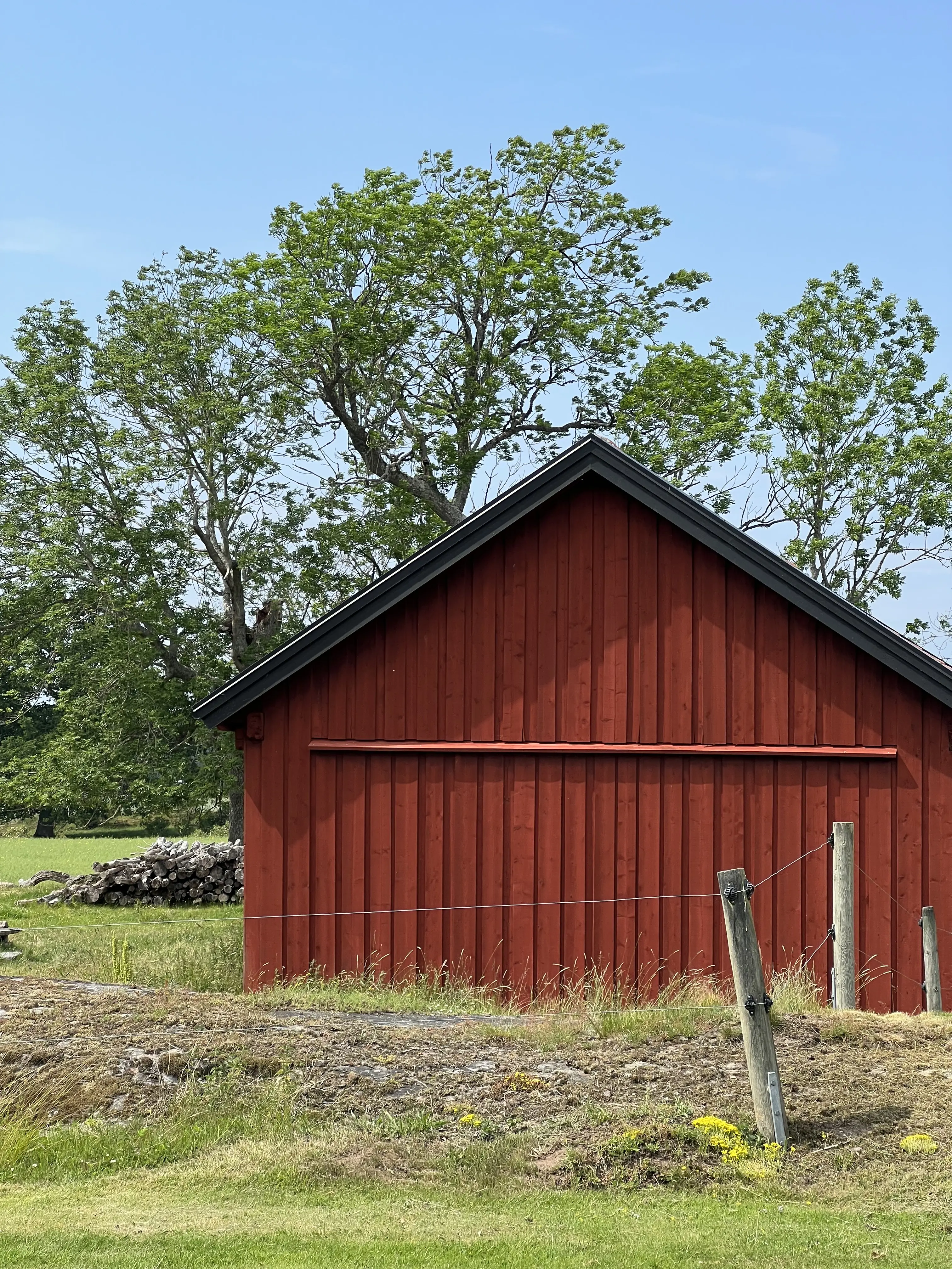 Änden av en röd byggnad med en hage framför.