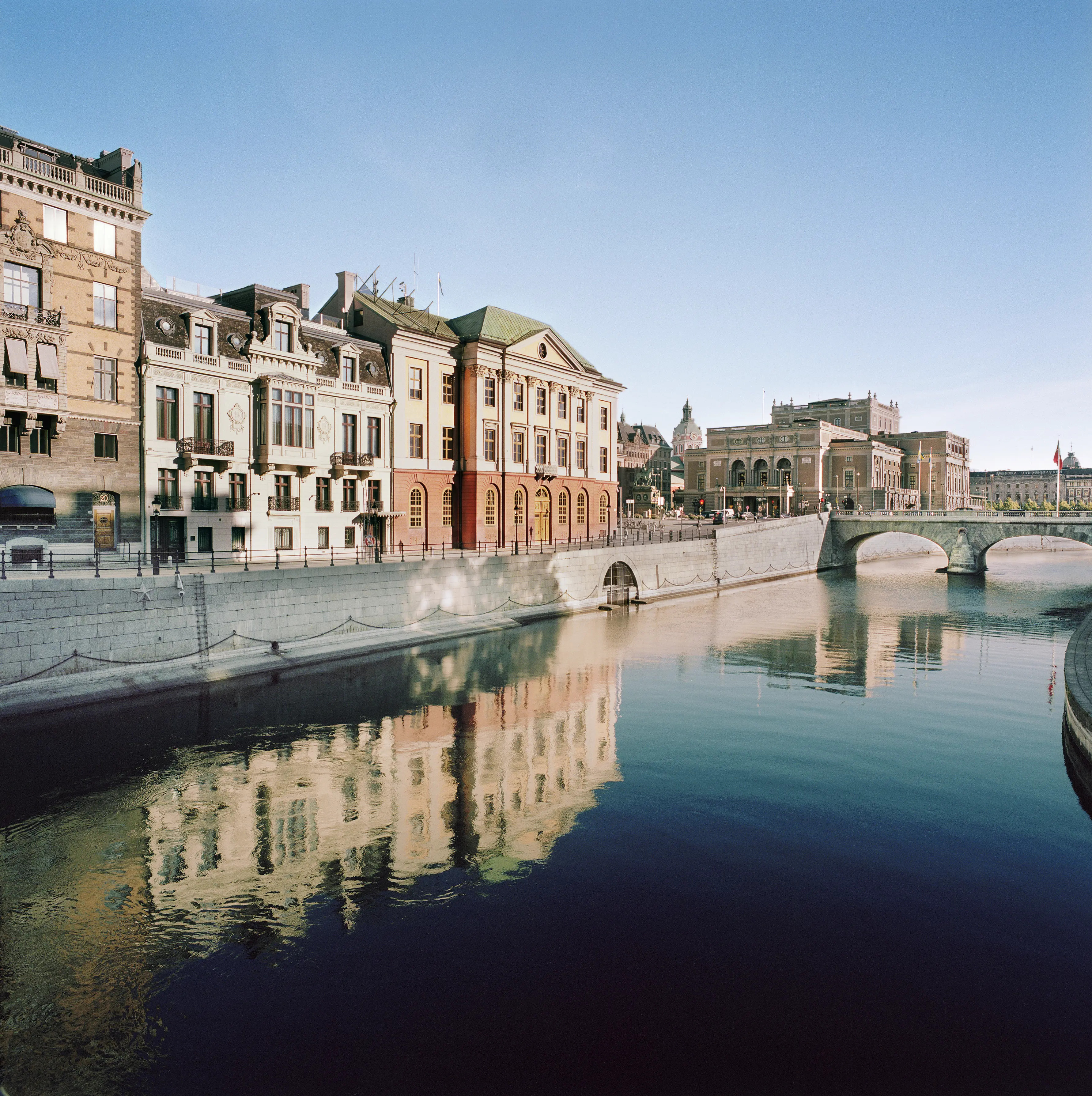 Sagerska husets vita fasad speglas i Norrström. Vy mot operahuset.