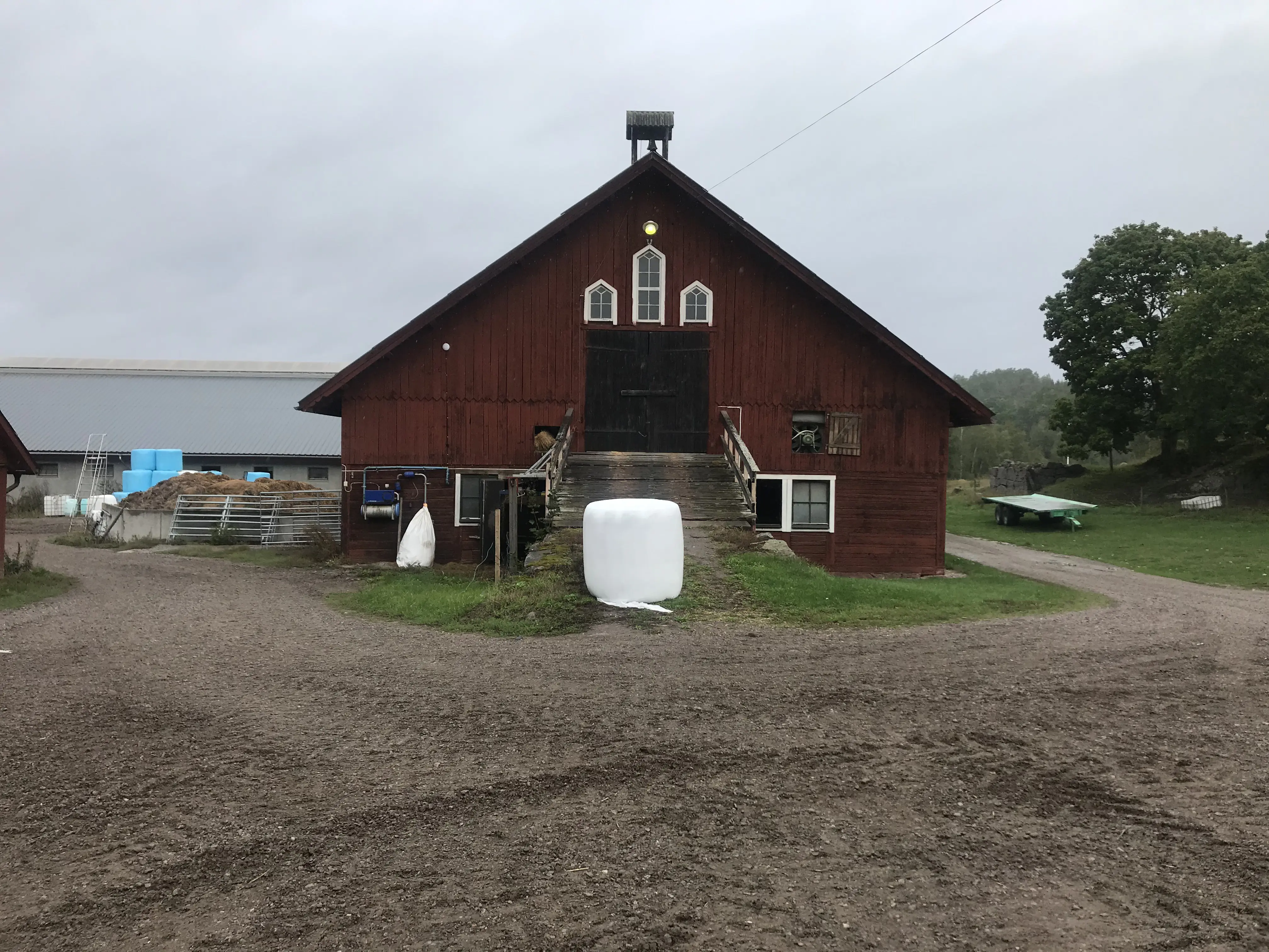 Ladugården på Herrsäter. En stor, rödmålad träbyggnad med vällingklocka på taket.