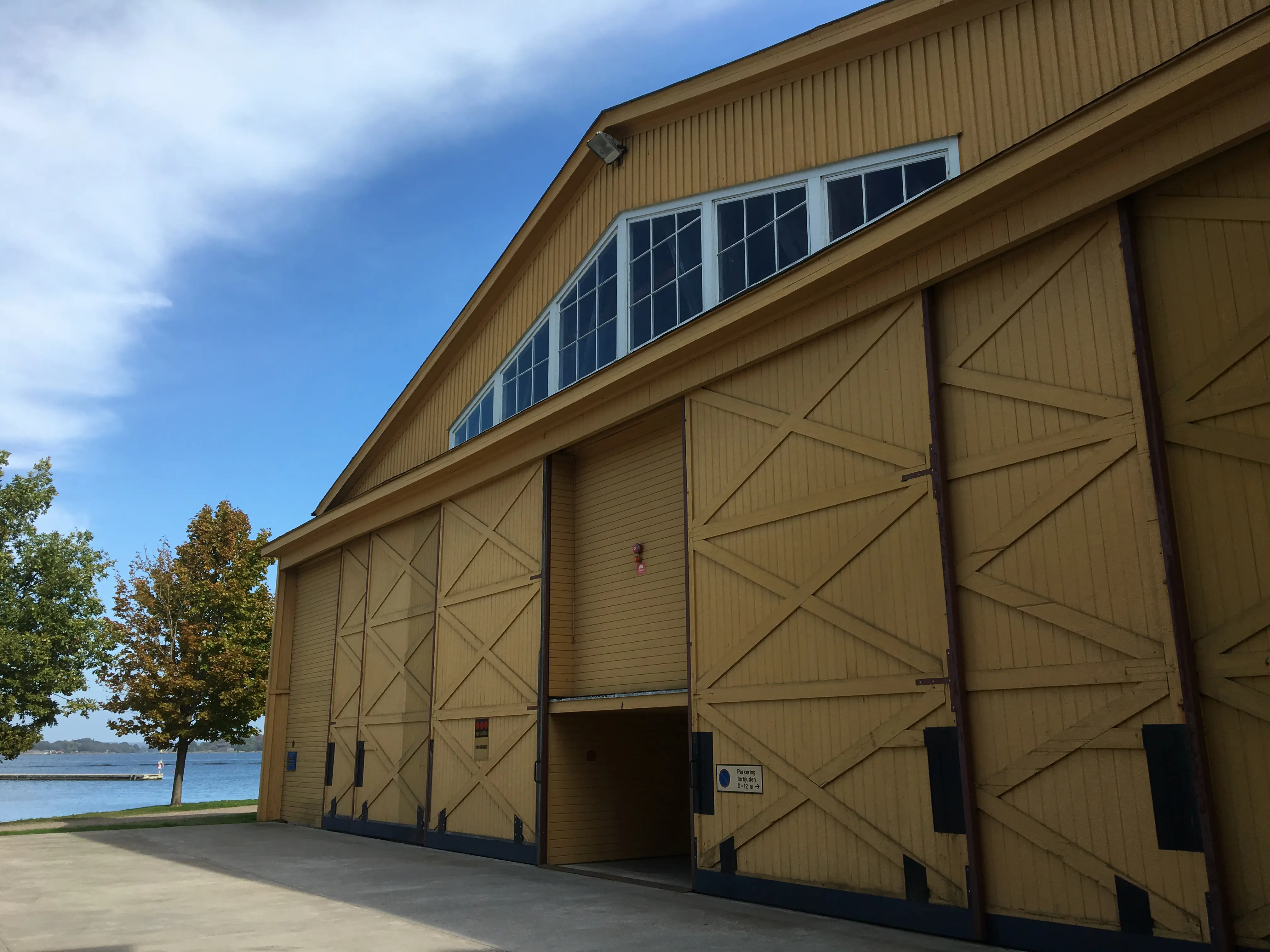 Lilla flyghangaren på Stumholmen i Karlskrona. En gul träbyggnad med stora skjutdörrar.